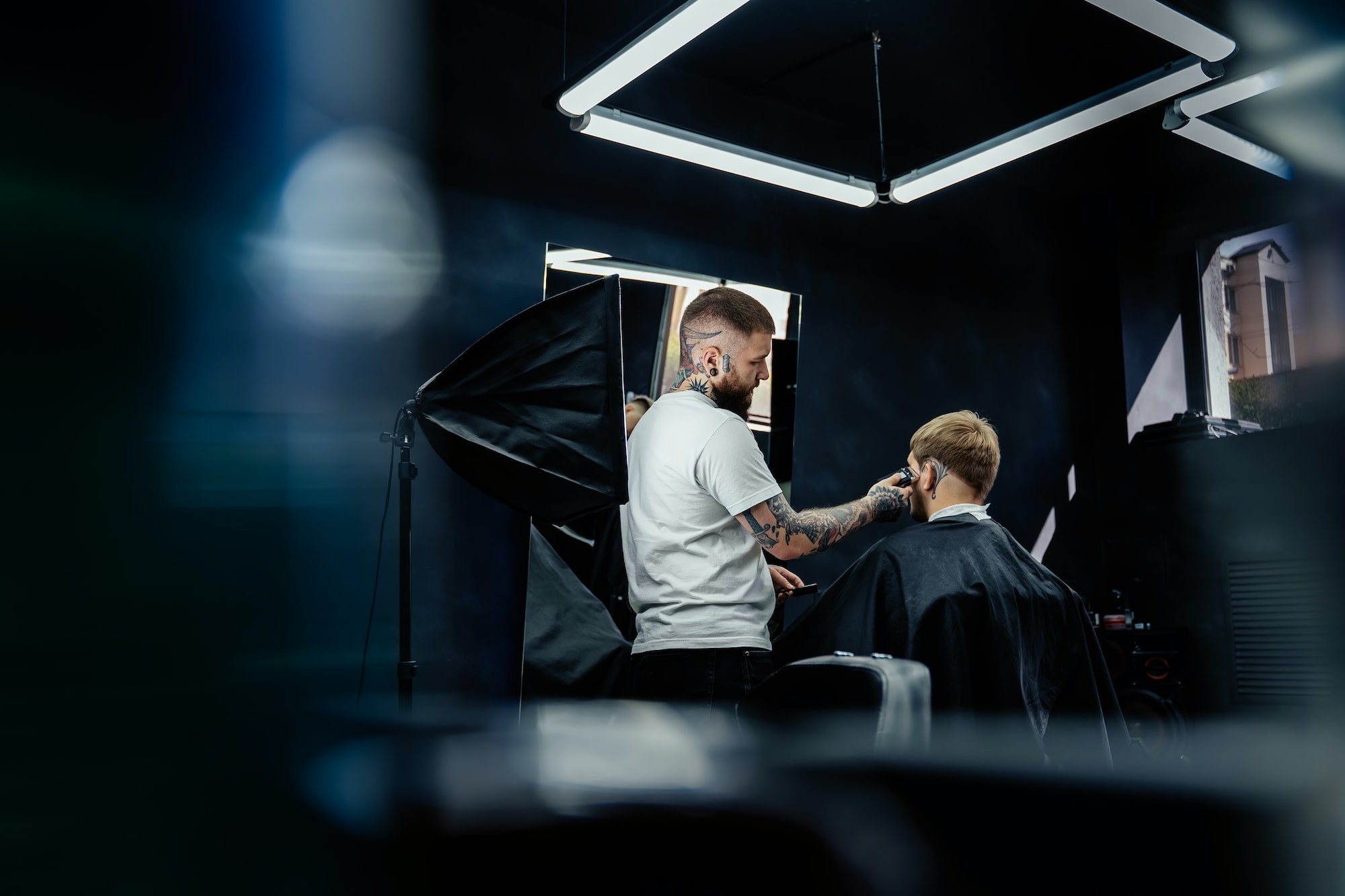 Male haircut with electric razor. Tattooed Barber makes haircut for client at the barber shop by