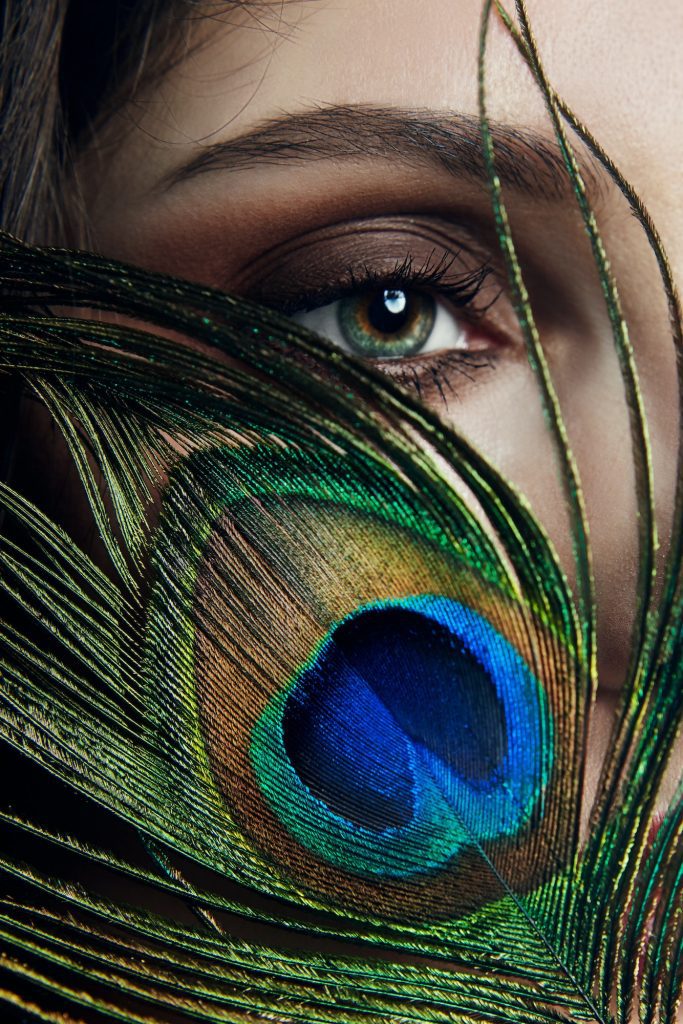 Eastern Arab woman with a peacock feather in her hands near her face. Beauty fashion makeup Arab