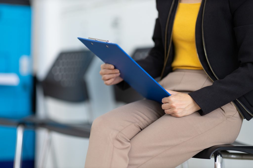 Waiting for interview, Confident businesswoman holding resume while sitting on chair.